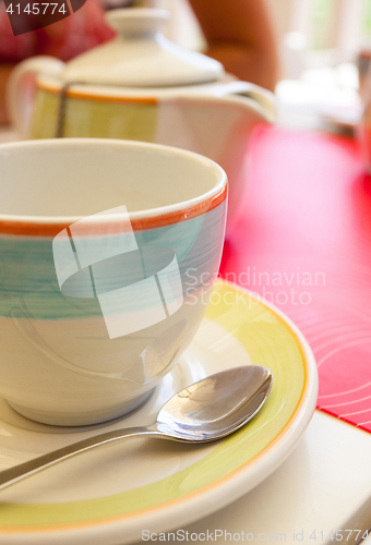 Image of tea cup with a spoon of sugar on table