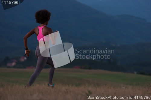 Image of Young African american woman jogging in nature