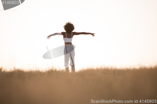 Image of young black girl dances outdoors in a meadow