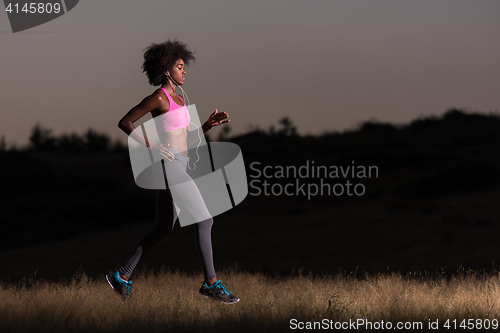 Image of Young African american woman jogging in nature