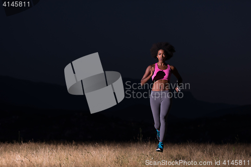 Image of Young African american woman jogging in nature