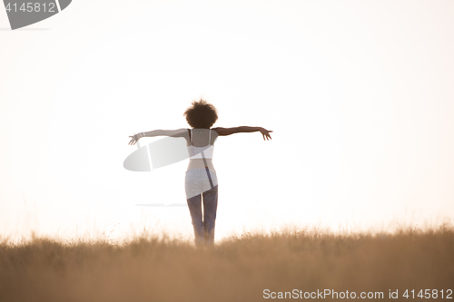 Image of young black girl dances outdoors in a meadow