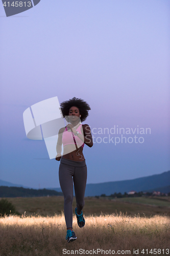 Image of Young African american woman jogging in nature