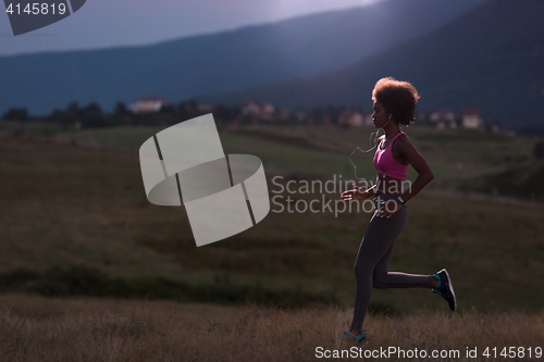 Image of Young African american woman jogging in nature