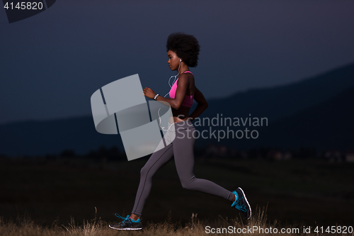 Image of Young African american woman jogging in nature