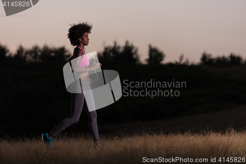 Image of Young African american woman jogging in nature