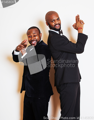 Image of two afro-american businessmen in black suits emotional posing, gesturing, smiling. wearing bow-ties