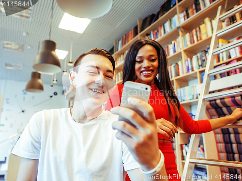 Image of couple students in univercity library, looking book, preparing to exam, having fun, making selfie, lifestyle people concept