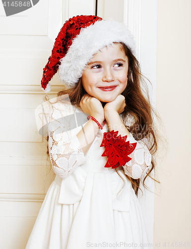 Image of little cute girl in santas red hat waiting for Christmas gifts. 