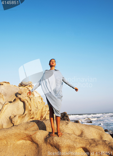 Image of beauty young woman among rocks at sea dreaming relaxing