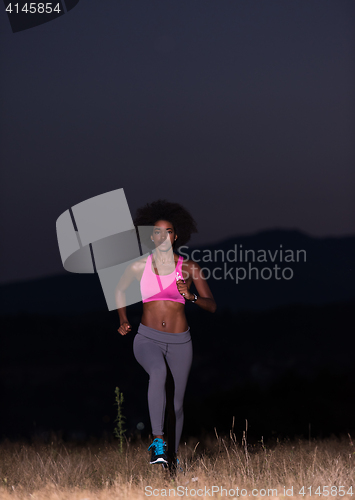 Image of Young African american woman jogging in nature