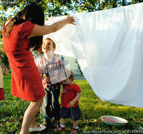 Image of woman with children in garden hanging laundry outside, playing with cute baby girl toddler, lifestyle people concept