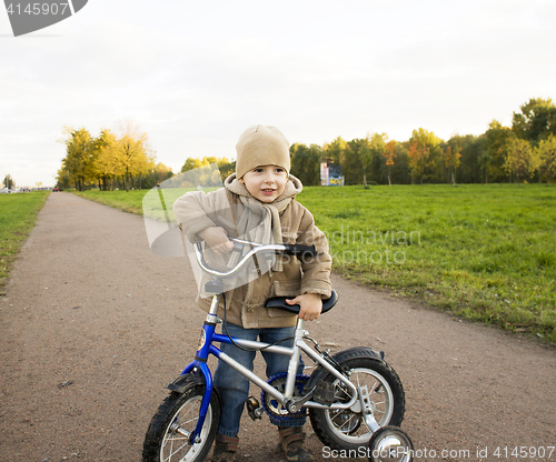 Image of little cute real boy on bicycle emotional smiling close up outside in green amusement park