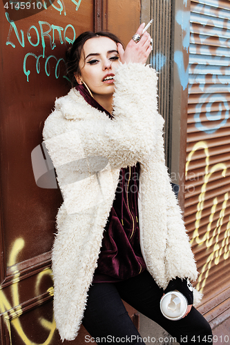 Image of young pretty stylish teenage girl outside in city wall with graf