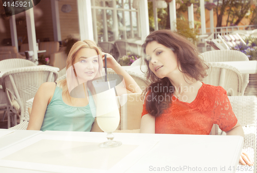 Image of portrait of two pretty modern girl friends in cafe open air interior drinking and talking, having chat and coctail, lifestyle friendship concept