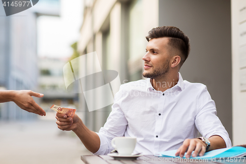 Image of man with euro money paying for coffee at cafe