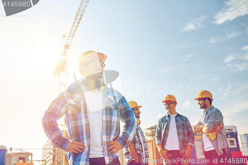 Image of group of smiling builders in hardhats outdoors