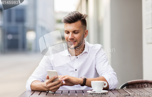 Image of man with smartphone and coffee at city cafe