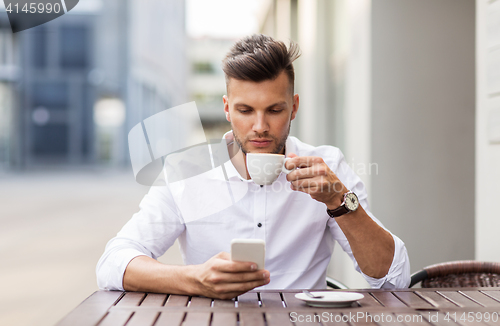 Image of man with smartphone drinking coffee at city cafe