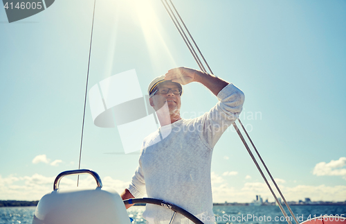 Image of senior man at helm on boat or yacht sailing in sea