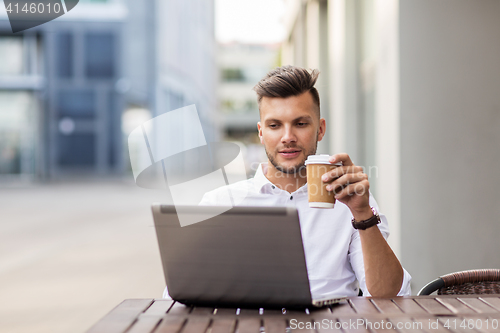 Image of man with laptop and coffee at city cafe