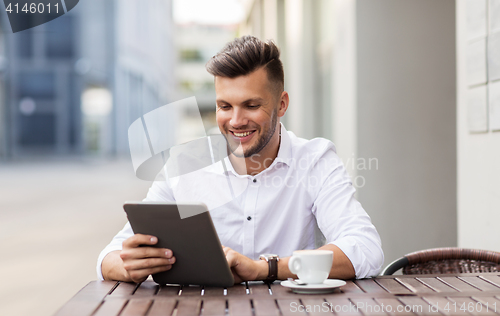 Image of man with tablet pc and coffee at city cafe