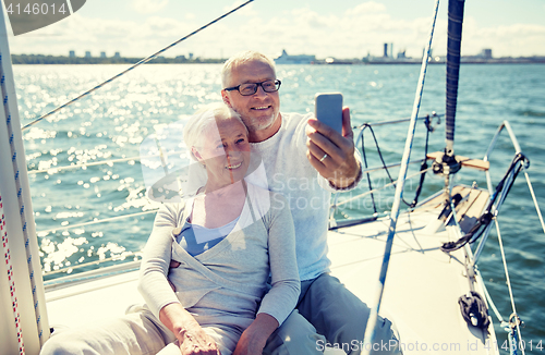Image of seniors with smartphone taking selfie on yacht