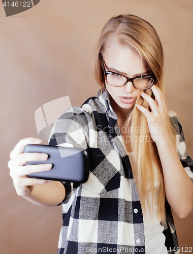 Image of young pretty blond hipster girl making selfie on warm brown background, lifestyle people concept