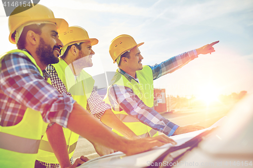 Image of close up of builders with blueprint on car hood