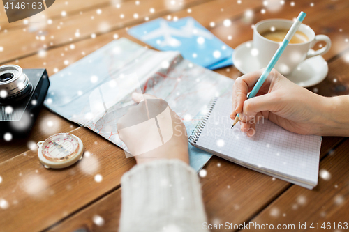 Image of hands with map and coffee writing to notebook