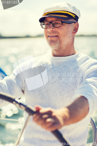 Image of senior man at helm on boat or yacht sailing in sea