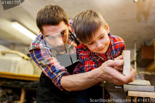 Image of father and little son with wood plank at workshop