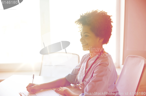 Image of happy female doctor or nurse writing at hospital