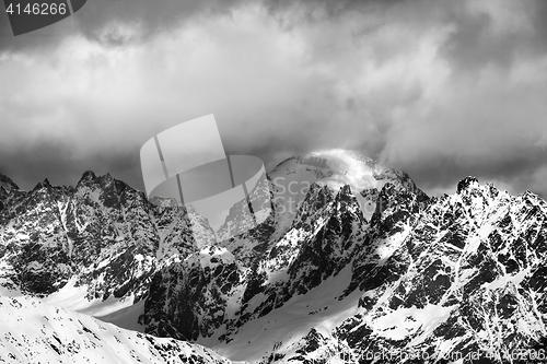 Image of Black and white snow mountains in clouds at sunny winter day