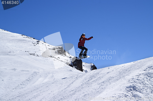 Image of Snowboarder jumping in snow park at ski resort on sun winter day