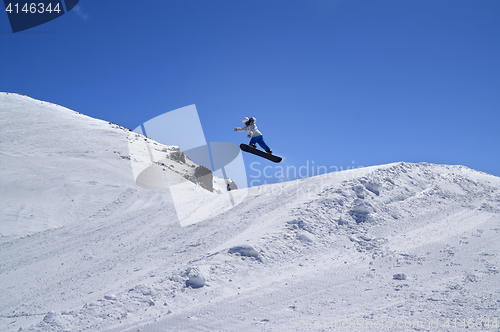 Image of Snowboarder jumping in snow park at ski resort on sunny winter d