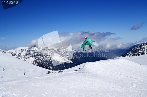 Image of Snowboarder jumping in snow park at winter mountain on nice sunn