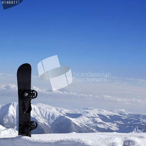 Image of Snowboard in snow near off-piste slope in sun day