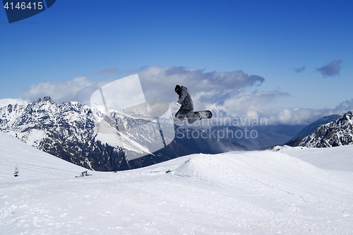 Image of Snowboarder jumping in snow mountains at sun winter day