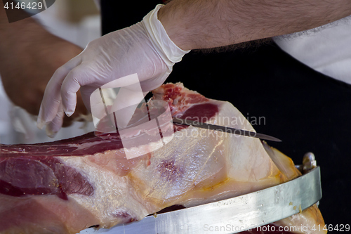 Image of Man slicing prosciutto famous and tasty mediterranean delicatess