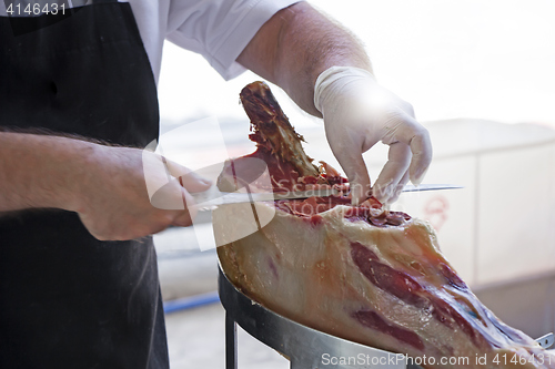 Image of Man slicing prosciutto famous and tasty mediterranean delicatess