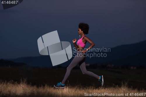 Image of Young African american woman jogging in nature