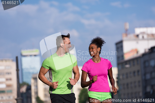 Image of young smiling multiethnic couple jogging in the city