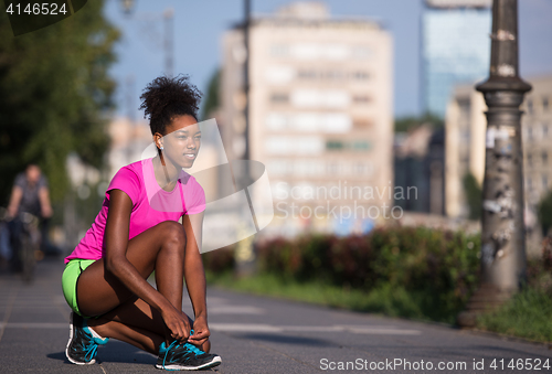 Image of African american woman runner tightening shoe lace