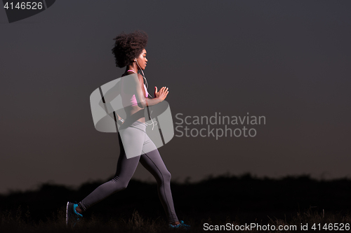 Image of Young African american woman jogging in nature