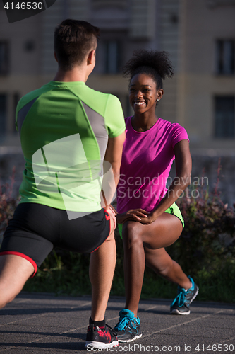 Image of jogging couple warming up and stretching in the city