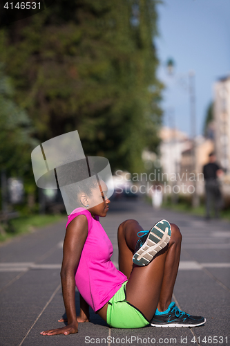 Image of sporty young african american woman stretching outdoors