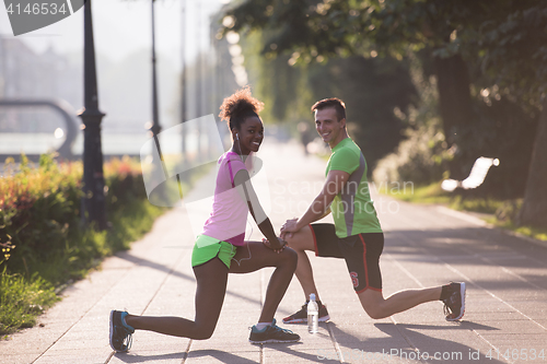 Image of jogging couple warming up and stretching in the city