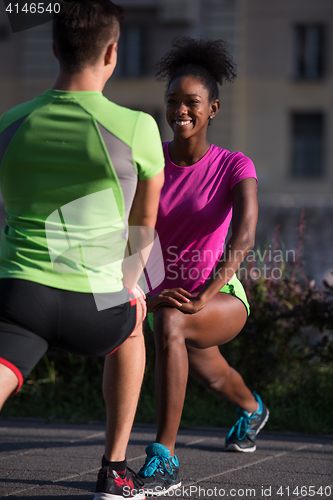 Image of jogging couple warming up and stretching in the city