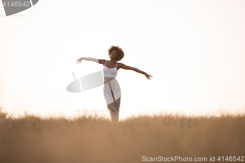 Image of young black girl dances outdoors in a meadow